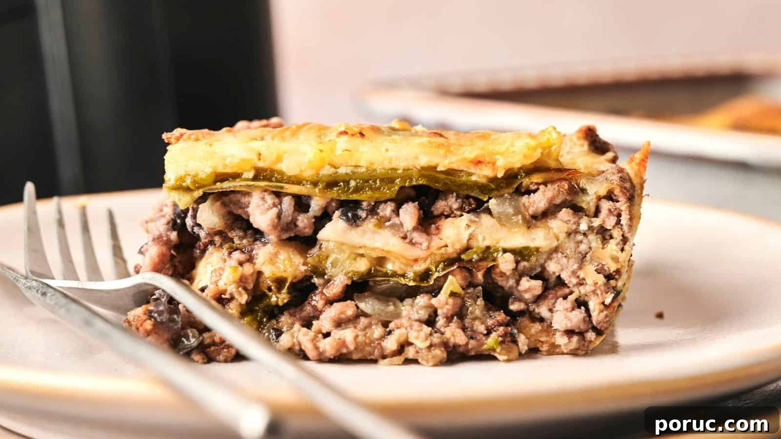 29 Air Fryer Casseroles Perfect for Busy Weeknight Dinners 17 Close-up of a slice of layered casserole with ground meat, cheese, and vegetables on a plate with a fork.