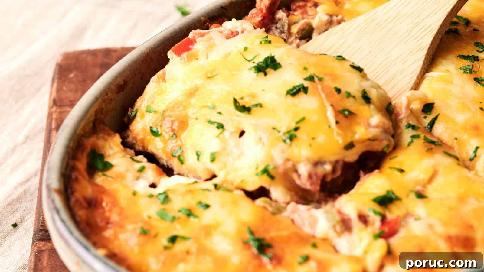 29 Air Fryer Casseroles Perfect for Busy Weeknight Dinners 18 A cheesy casserole with chopped herbs on top, being served with a wooden spatula, in a round baking dish.