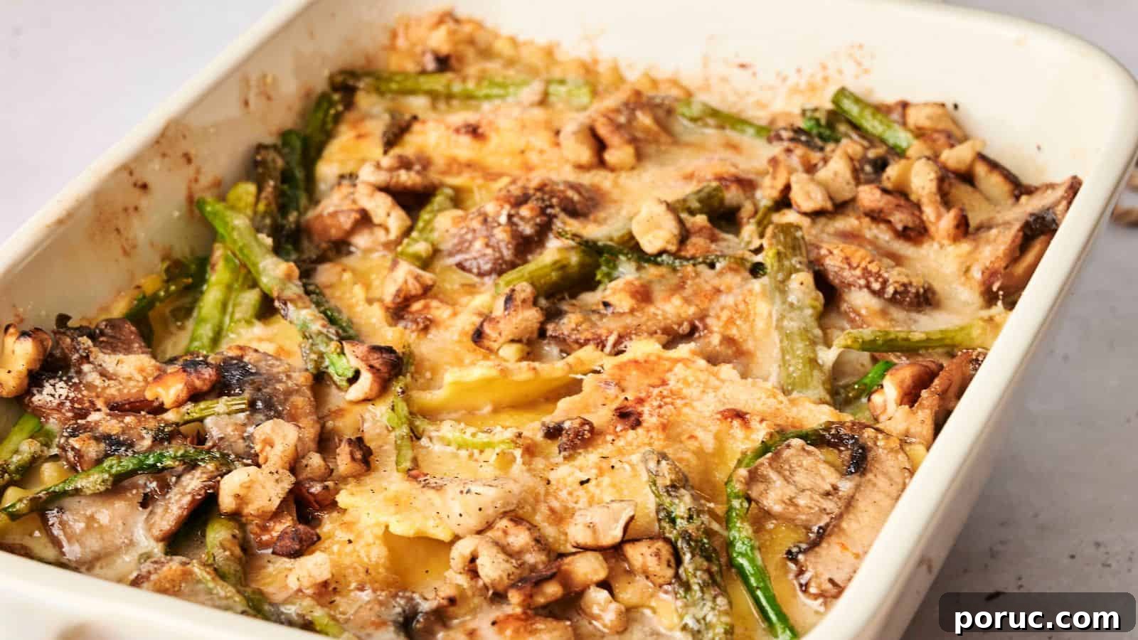29 Air Fryer Casseroles Perfect for Busy Weeknight Dinners 4 Baked dish with layered pasta, mushrooms, asparagus, and nuts in a creamy sauce, topped with a golden-brown crust, in a rectangular white baking dish.