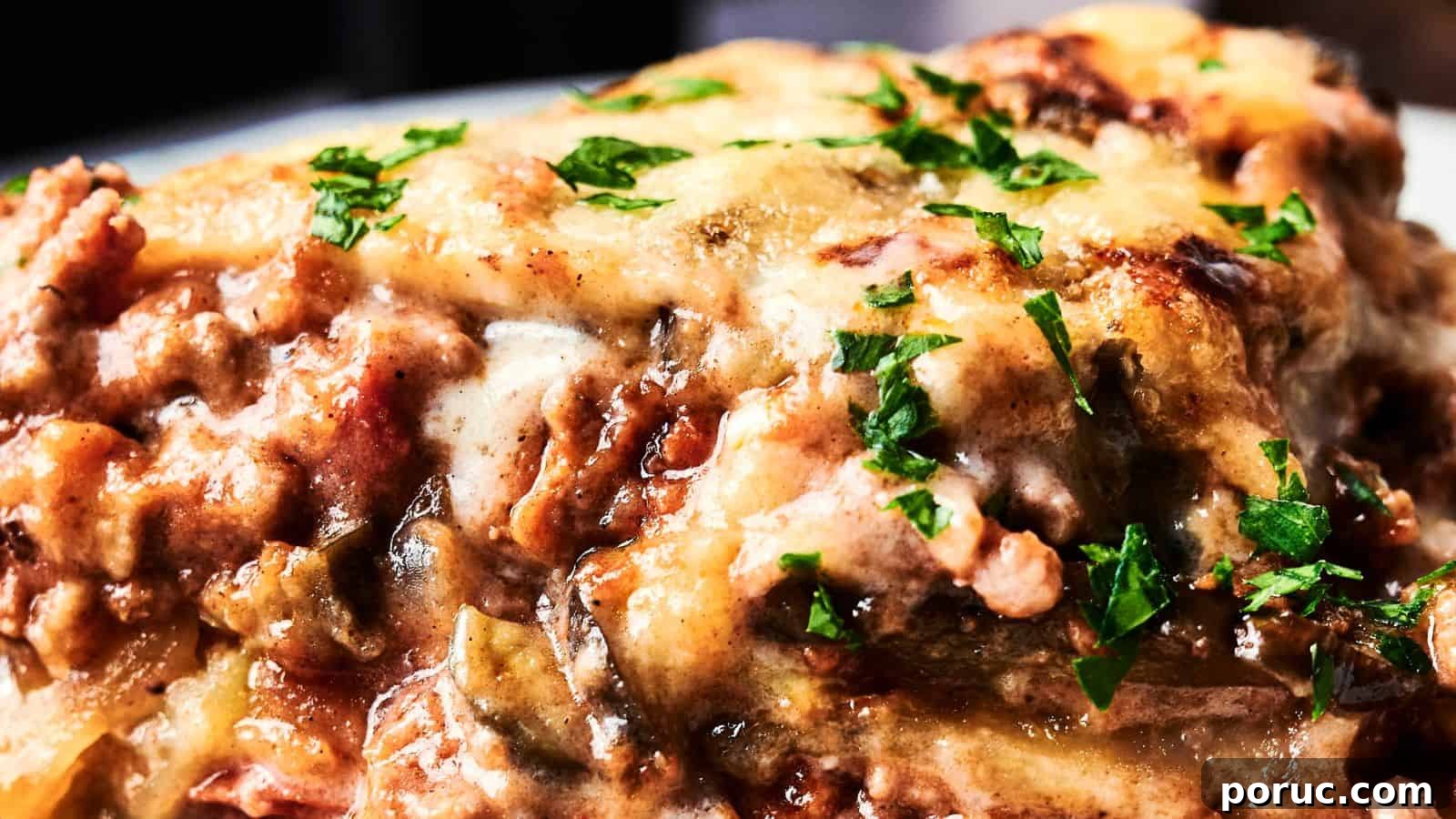 29 Air Fryer Casseroles Perfect for Busy Weeknight Dinners 5 Close-up of a cheesy, baked lasagna topped with chopped parsley and browned, melted cheese.