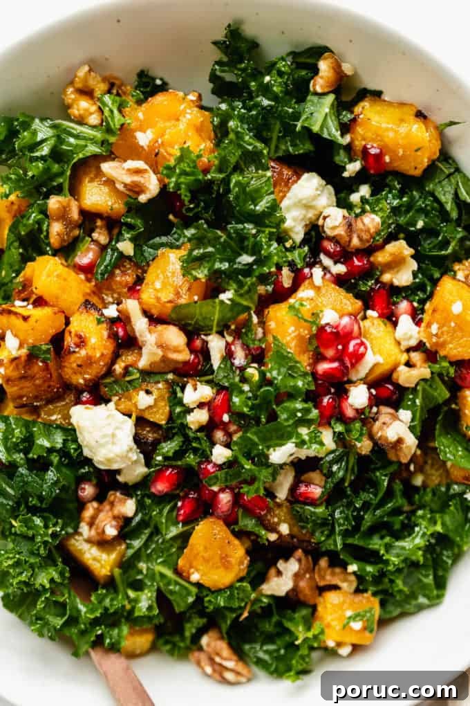 Roasted Pumpkin Salad with Maple Vinaigrette and Toasted Seeds 2 A close up of a kale and pumpkin salad topped with walnuts and pomegranate