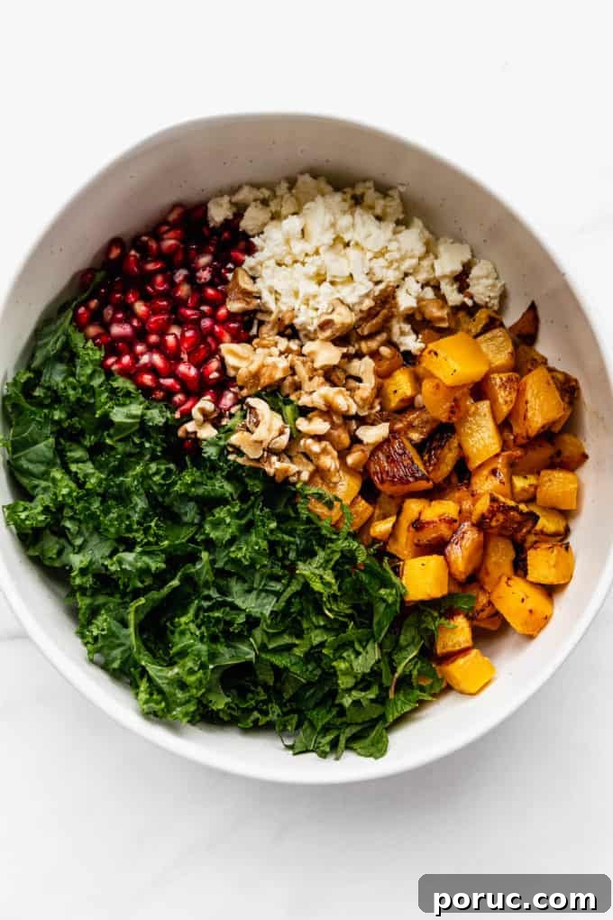 Roasted Pumpkin Salad with Maple Vinaigrette and Toasted Seeds 8 A white mixing bowl with kale, roasted pumpkin, walnuts, feta and pomegranate in it