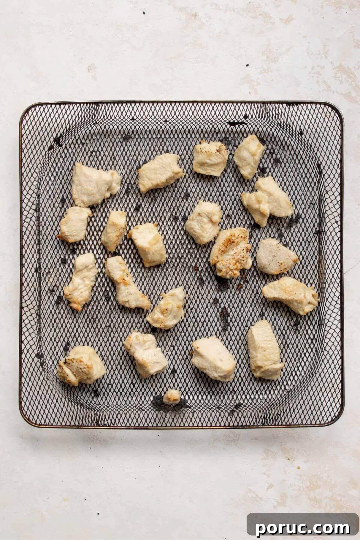 Crispy Air Fryer Orange Chicken Recipe You’ll Love 7 Cooked chicken pieces with crispy edges in an air fryer basket.