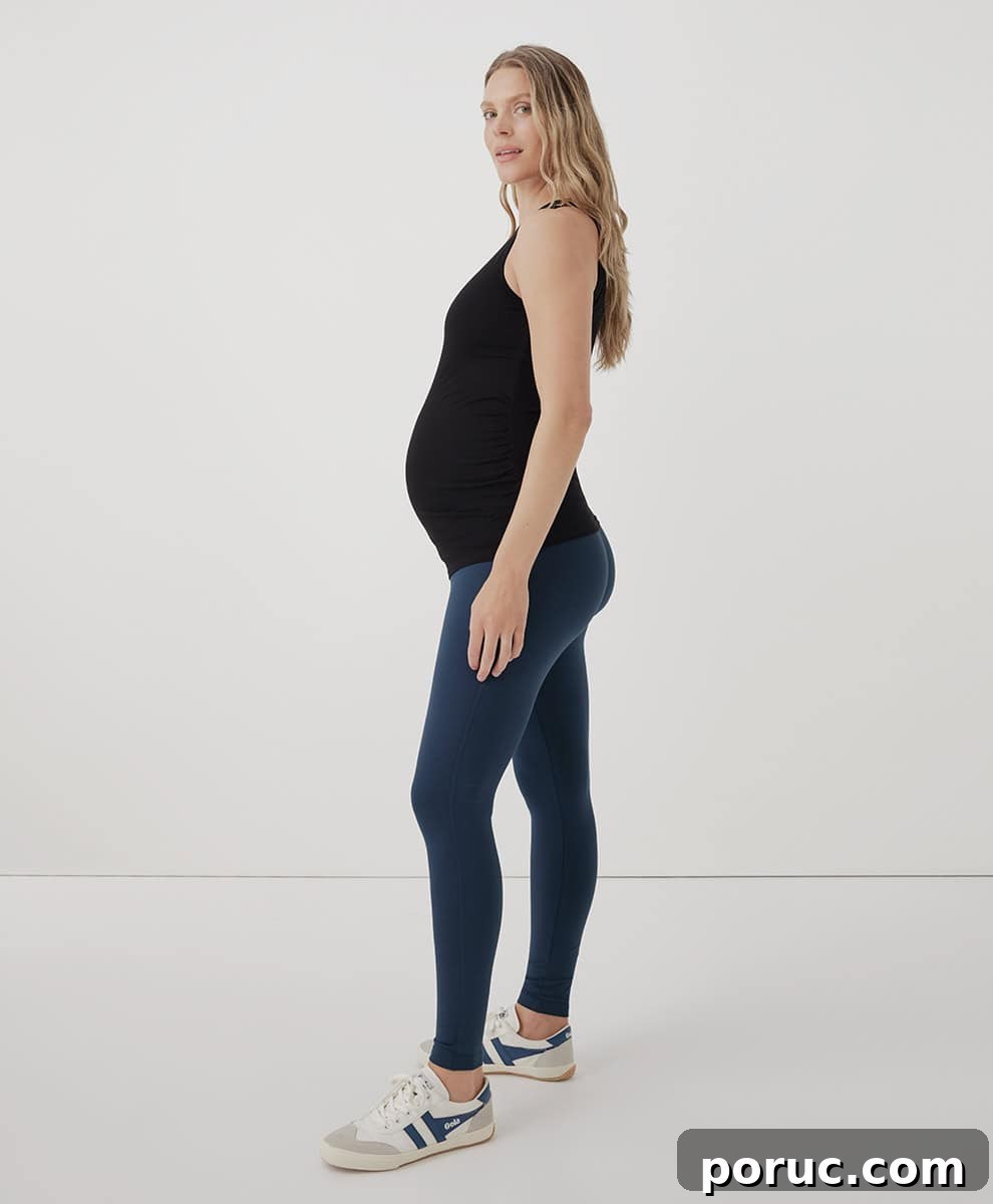 A pregnant woman wearing a Pact maternity top and leggings.