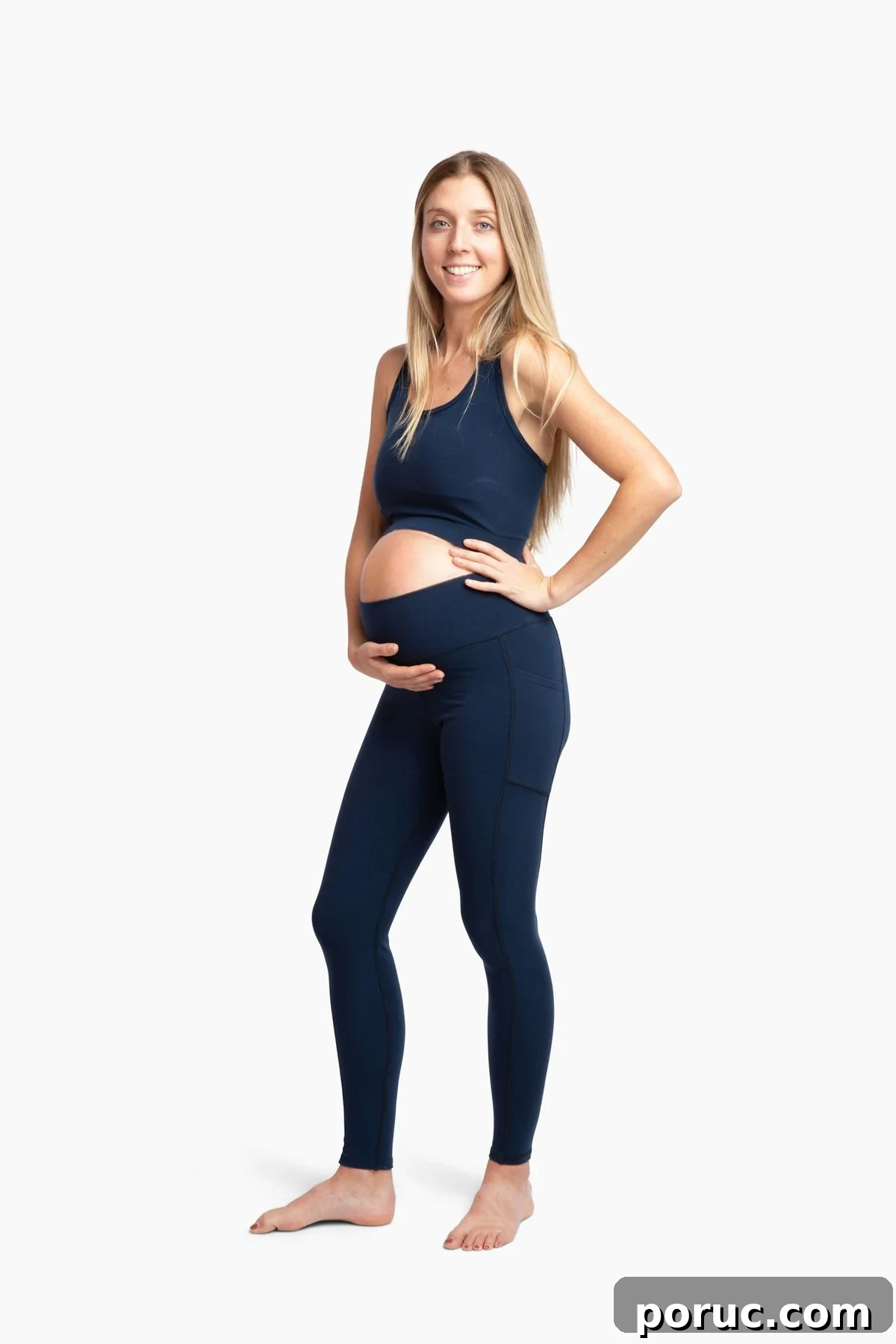 A smiling pregnant woman wearing navy maternity leggings from Reprise.