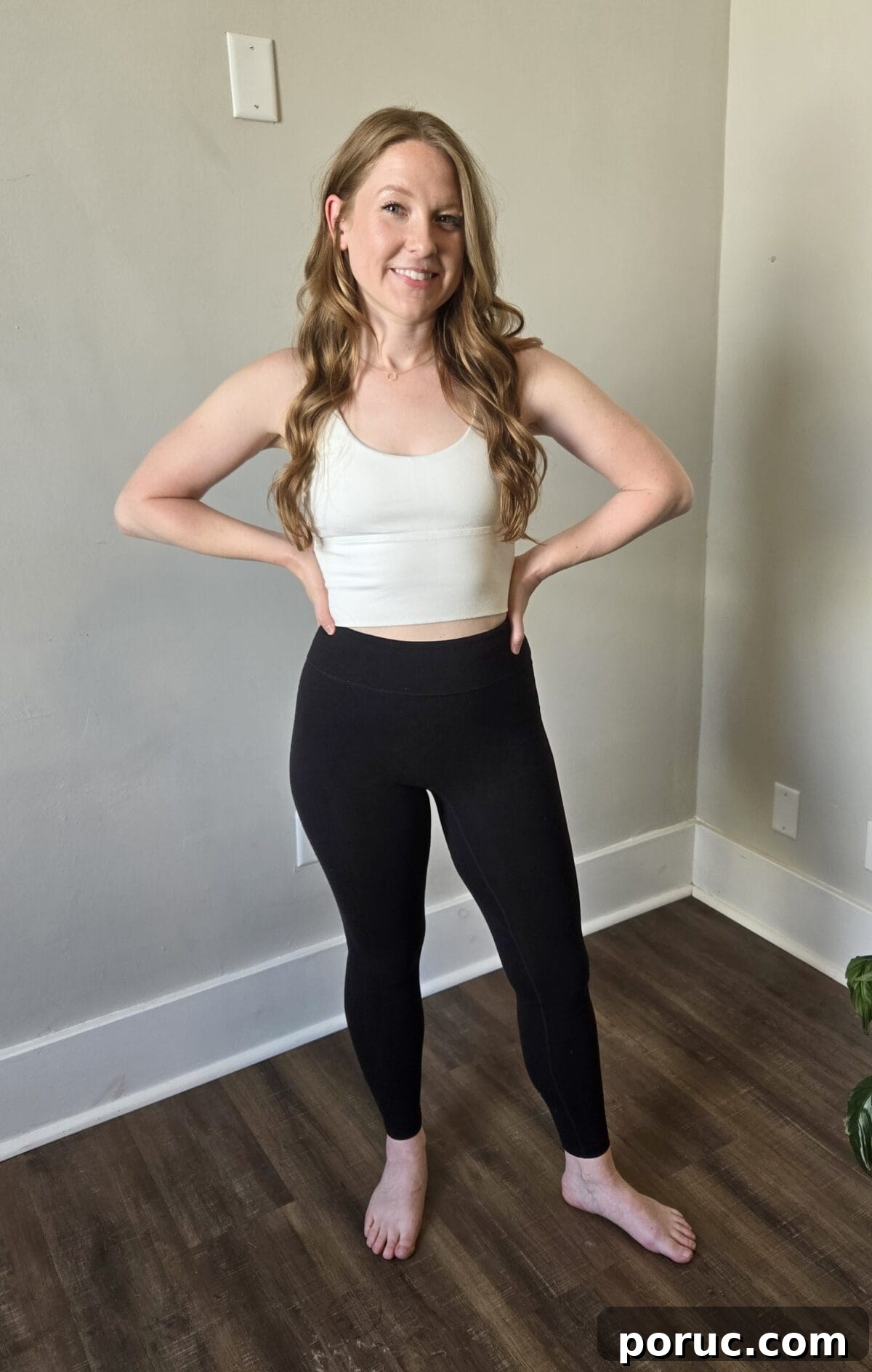 A smiling woman wearing Allwear black high-waisted leggings.