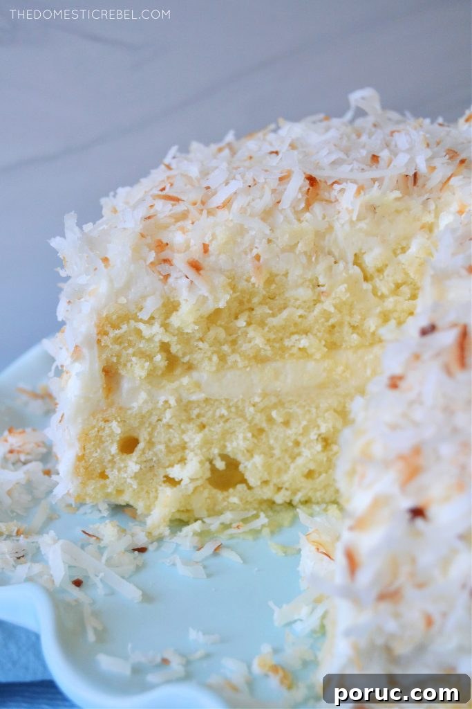 Ultimate Coconut Layer Cake Recipe for Moist, Classic Flavor 4 coconut layer cake on a blue pedestal