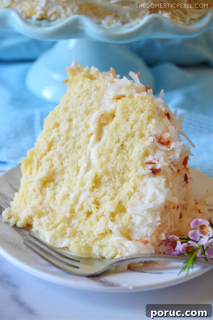 Ultimate Coconut Layer Cake Recipe for Moist, Classic Flavor 5 coconut layer cake slice with flowers and a fork on a plate