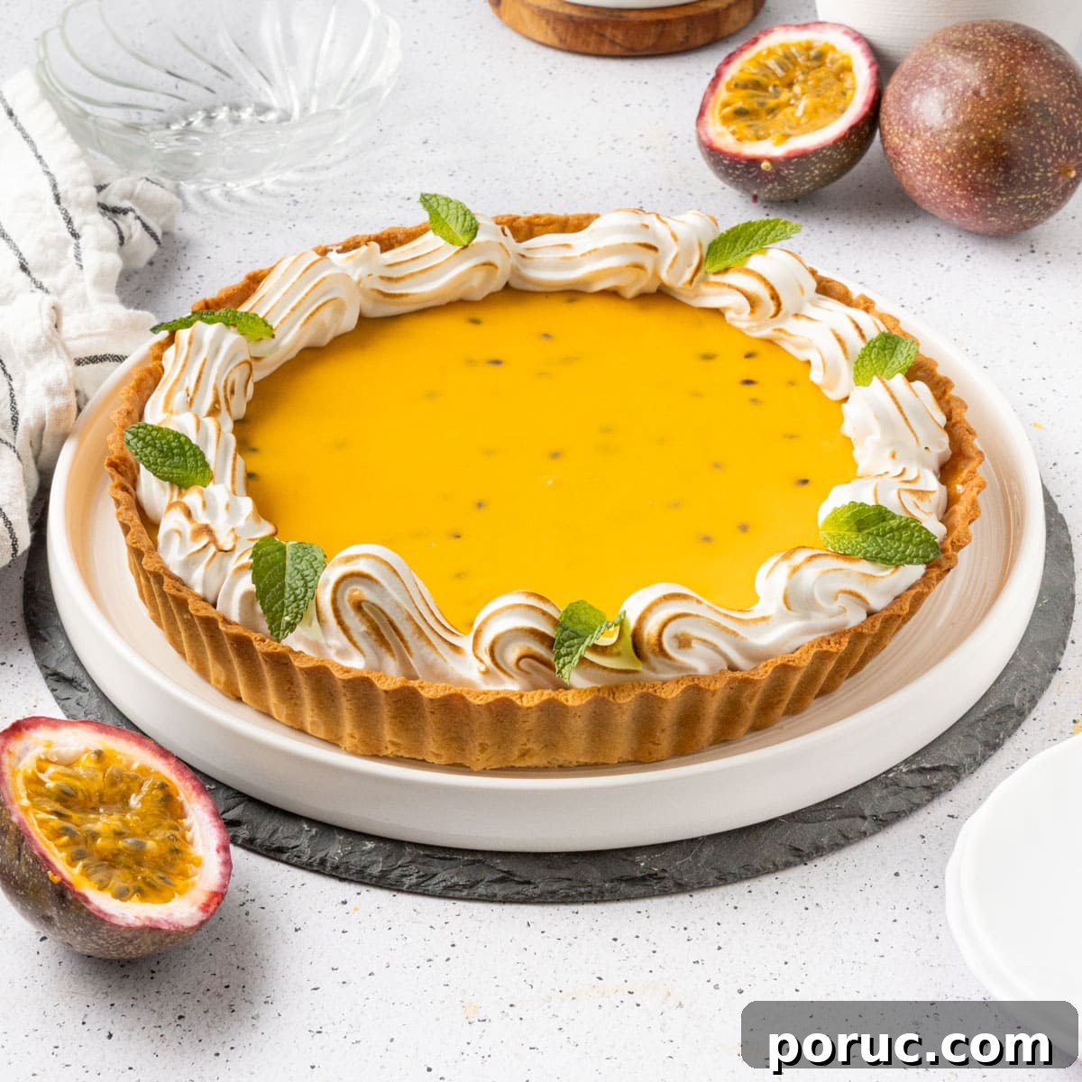 Passion fruit tart on a large white plate surrounded by fresh passion fruits.