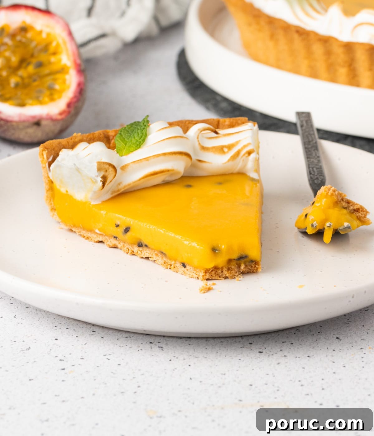 Slice of tart on a small white plate with a piece taken off and resting on a small fork.