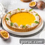 Passion fruit tart on a large white plate surrounded by fresh passion fruits.