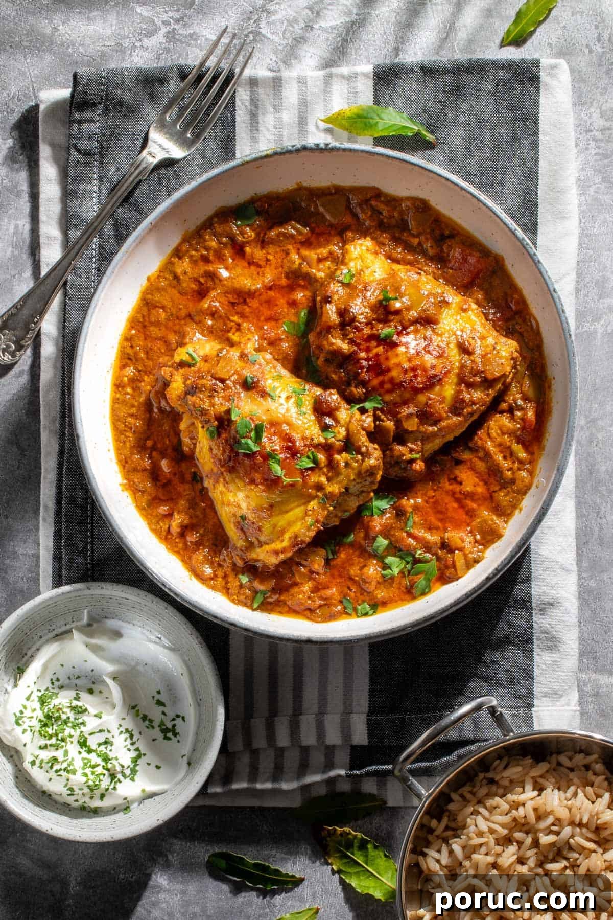 Authentic Nepali Chicken Curry Recipe: Traditional Taste Guide 2 Two pieces of Nepalese chicken curry in a white bowl on a grey and white tea towel.