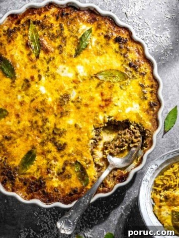 Easy South African bobotie in a white dish on a grey background.