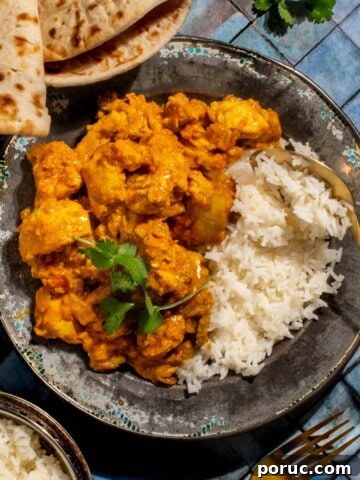 Chicken karahi curry in on a plate with rice on a blue background.