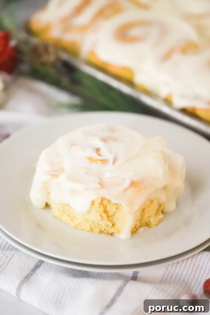 A frosted cinnamon roll on a white plate.