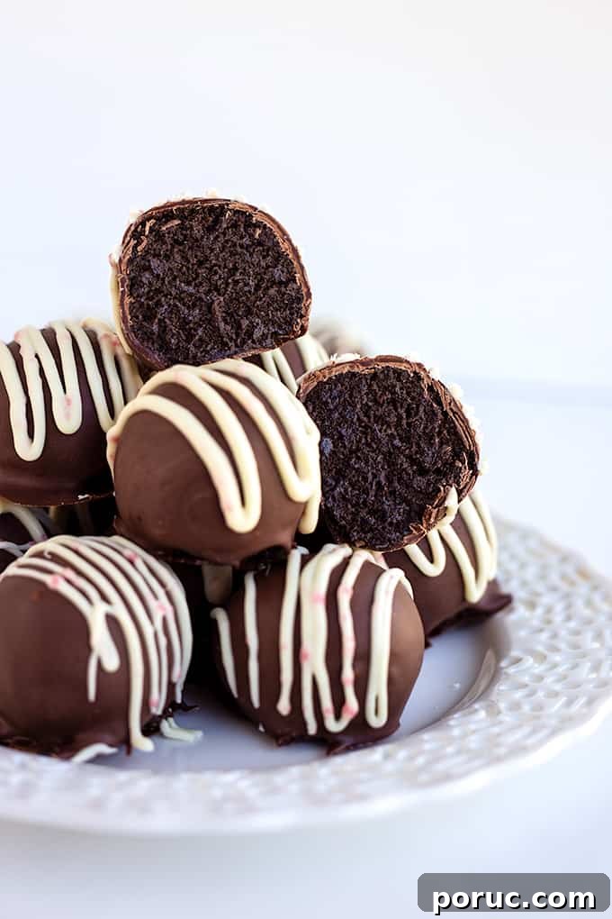 stack of peppermint oreo truffles on a white plate on a white background with an truffle cut in half