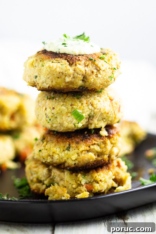 Crispy Salmon Croquettes with Lemon-Dill Sauce 4 Four salmon croquettes stacked in a tower on a black plate with remoulade and parsley on top