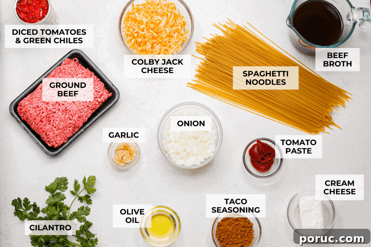 Taco spaghetti brings together two family favorites, tacos and pasta, in one cheesy, flavor packed dish! With taco-seasoned beef, melty cheese, and zesty tomatoes, it’s a weeknight win everyone will love. Overhead shot of labeled taco spaghetti ingredients.