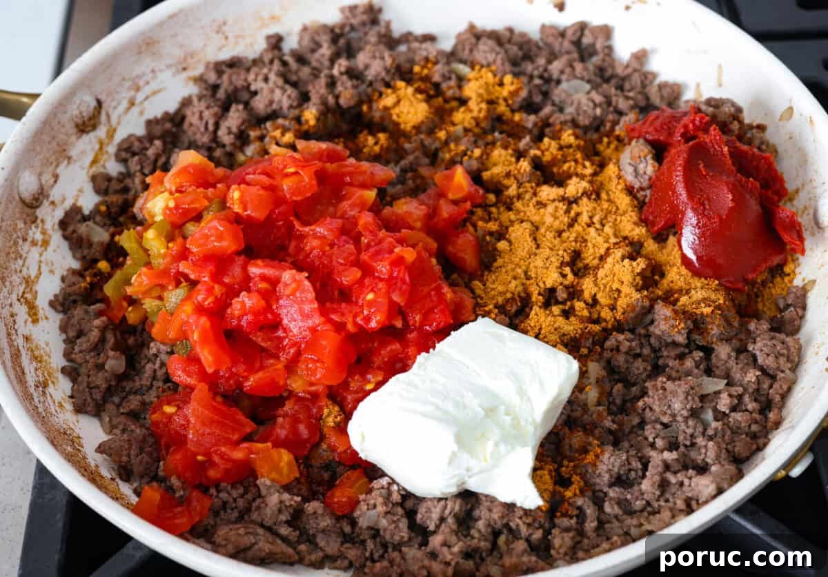 Taco spaghetti brings together two family favorites, tacos and pasta, in one cheesy, flavor packed dish! With taco-seasoned beef, melty cheese, and zesty tomatoes, it’s a weeknight win everyone will love. Cooked beef and onions with seasonings, rotel, cream cheese, and beef broth added.