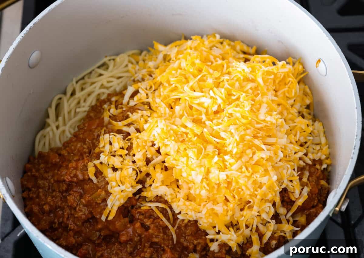 Taco spaghetti brings together two family favorites, tacos and pasta, in one cheesy, flavor packed dish! With taco-seasoned beef, melty cheese, and zesty tomatoes, it’s a weeknight win everyone will love. Meat mixture and cheese added to the pan with the pasta.