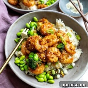 Mongolian Shrimp and Broccoli Stir-Fry Recipe 9 Mongolian shrimp in a grey bowl with edamame and a gold fork.