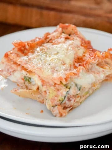 A slice of the vegetable lasagna is on white plates with a cutting board behind it.