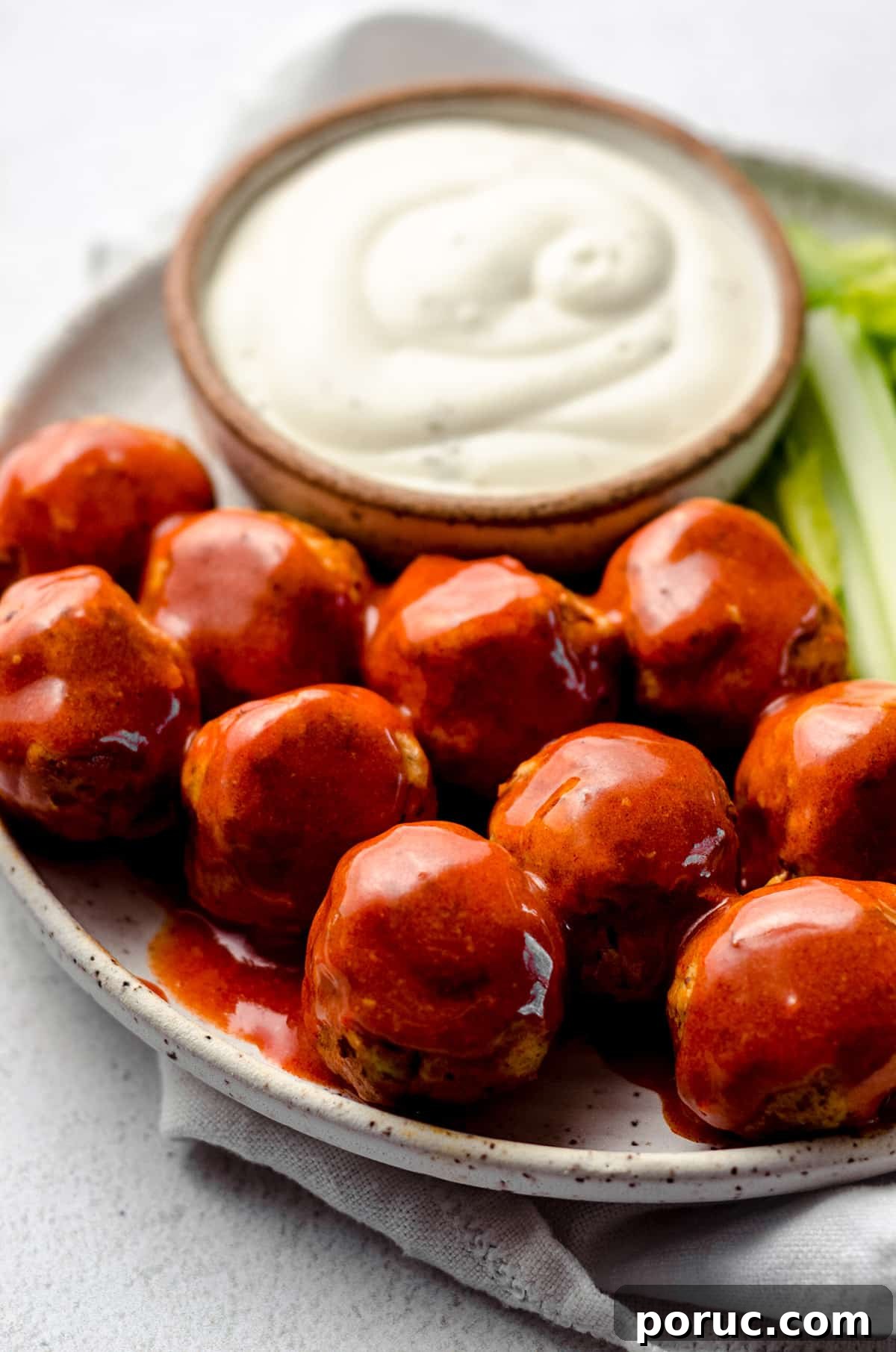 A plate of meatballs with a creamy sauce on the side.