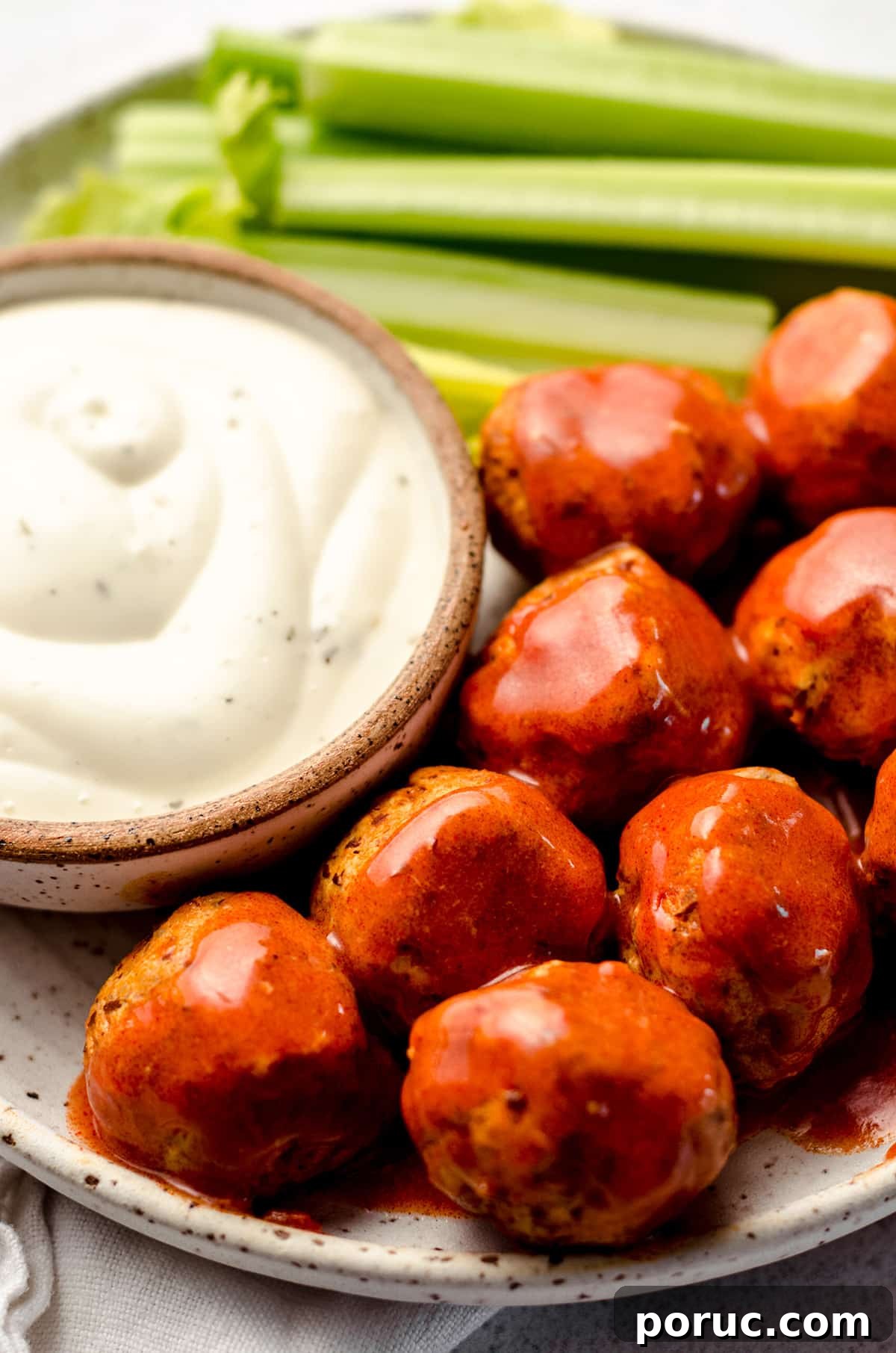 A plate filled with meatballs, celery and creamy dressing.