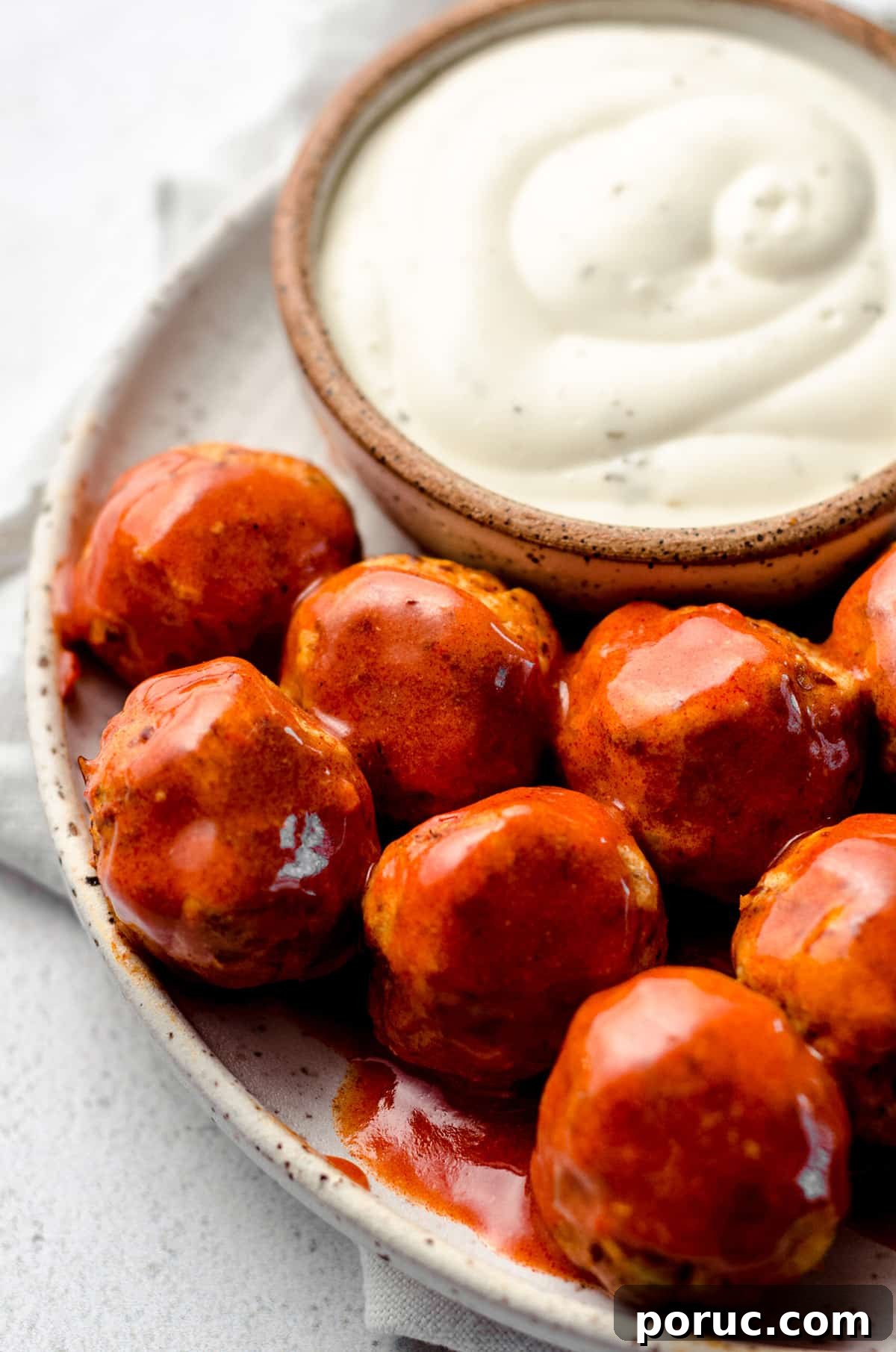 A plate filled with buffalo sauce covered meatballs.