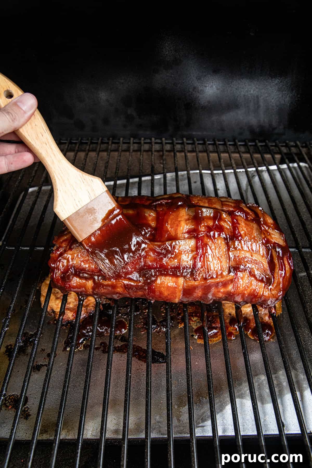 Ultimate Bacon Explosion Recipe: Stuffed Bacon-Wrapped Meatloaf 13 Smearing BBQ sauce on stuffed bacon weave for Bacon Explosion recipe