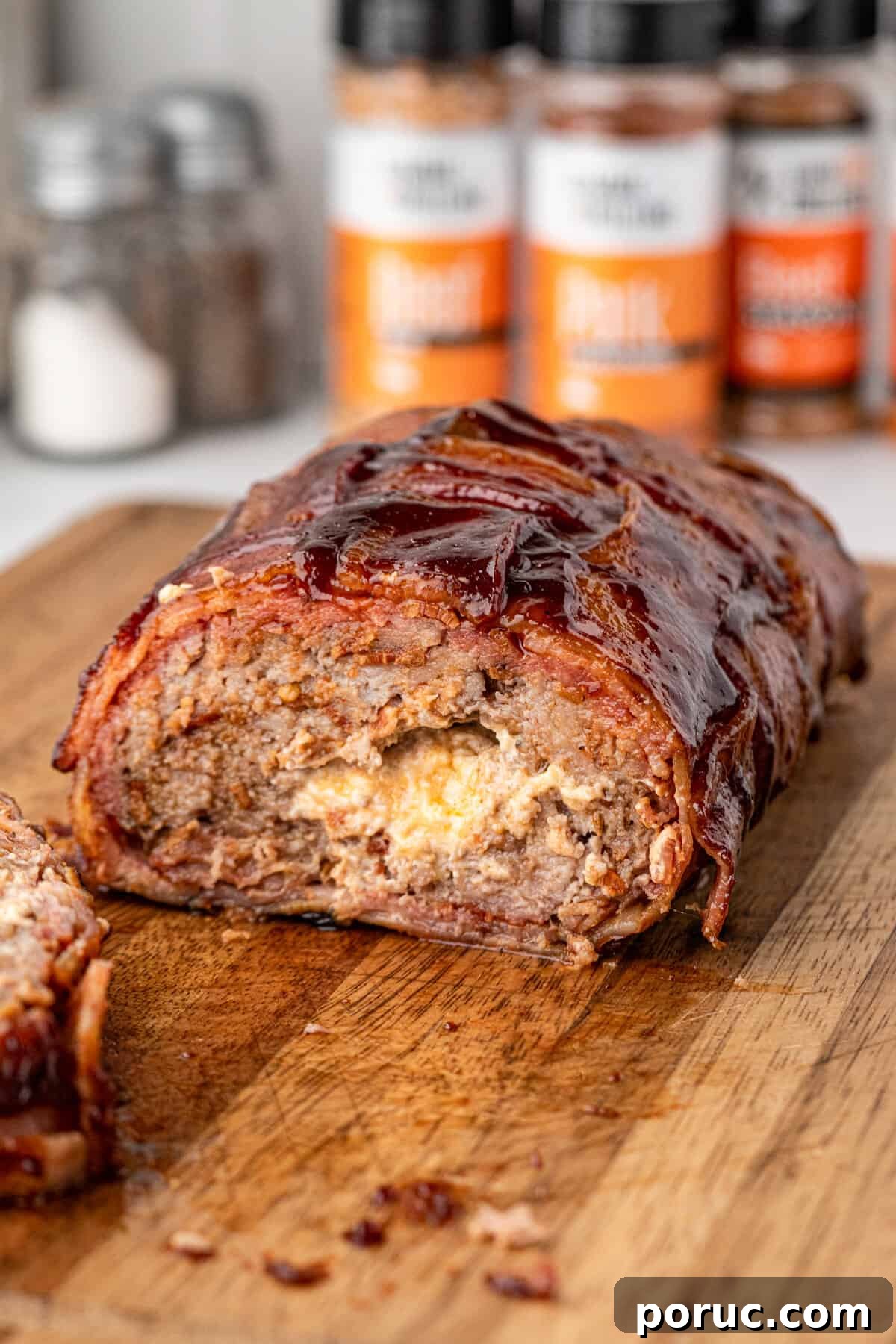 Ultimate Bacon Explosion Recipe: Stuffed Bacon-Wrapped Meatloaf 15 Bacon Explosion sliced open on wooden cutting board