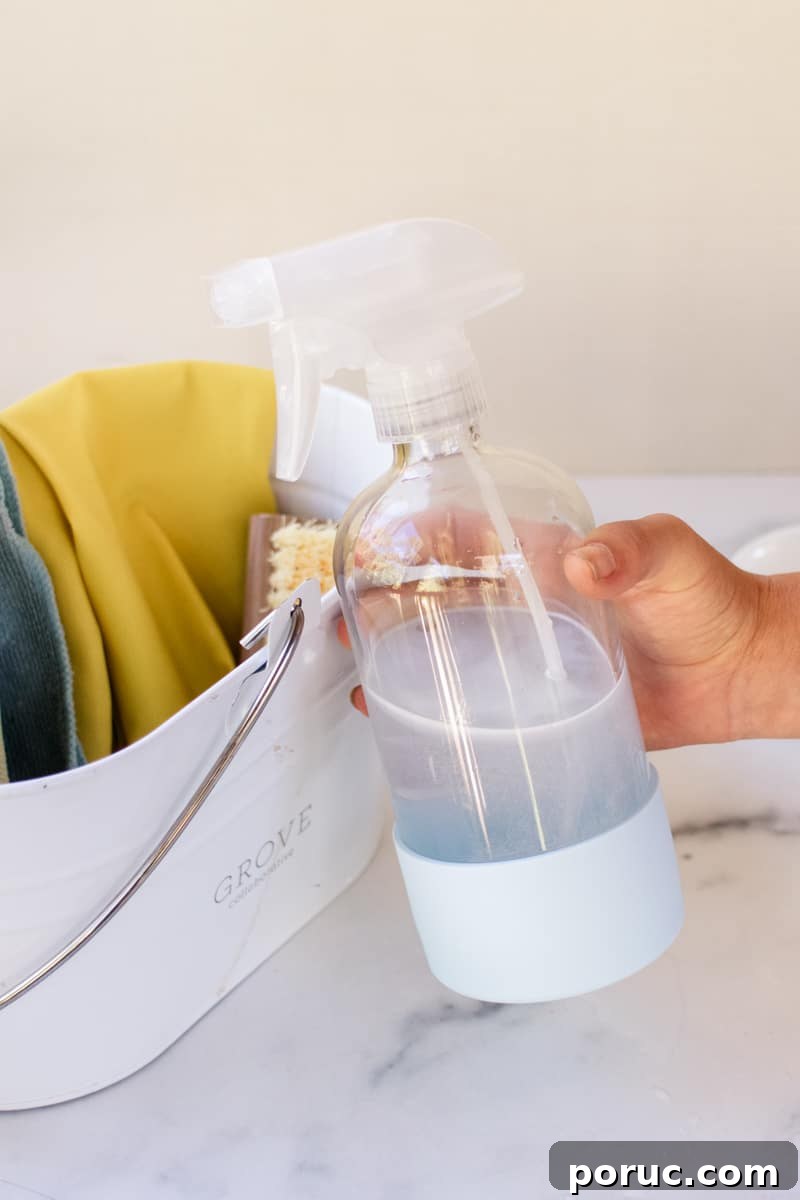 Remove Mold from Shower Grout Fast: Proven Step-by-Step Method 10 A bottle of homemade tile grout mold spray in front of a pail with rags and a brush.