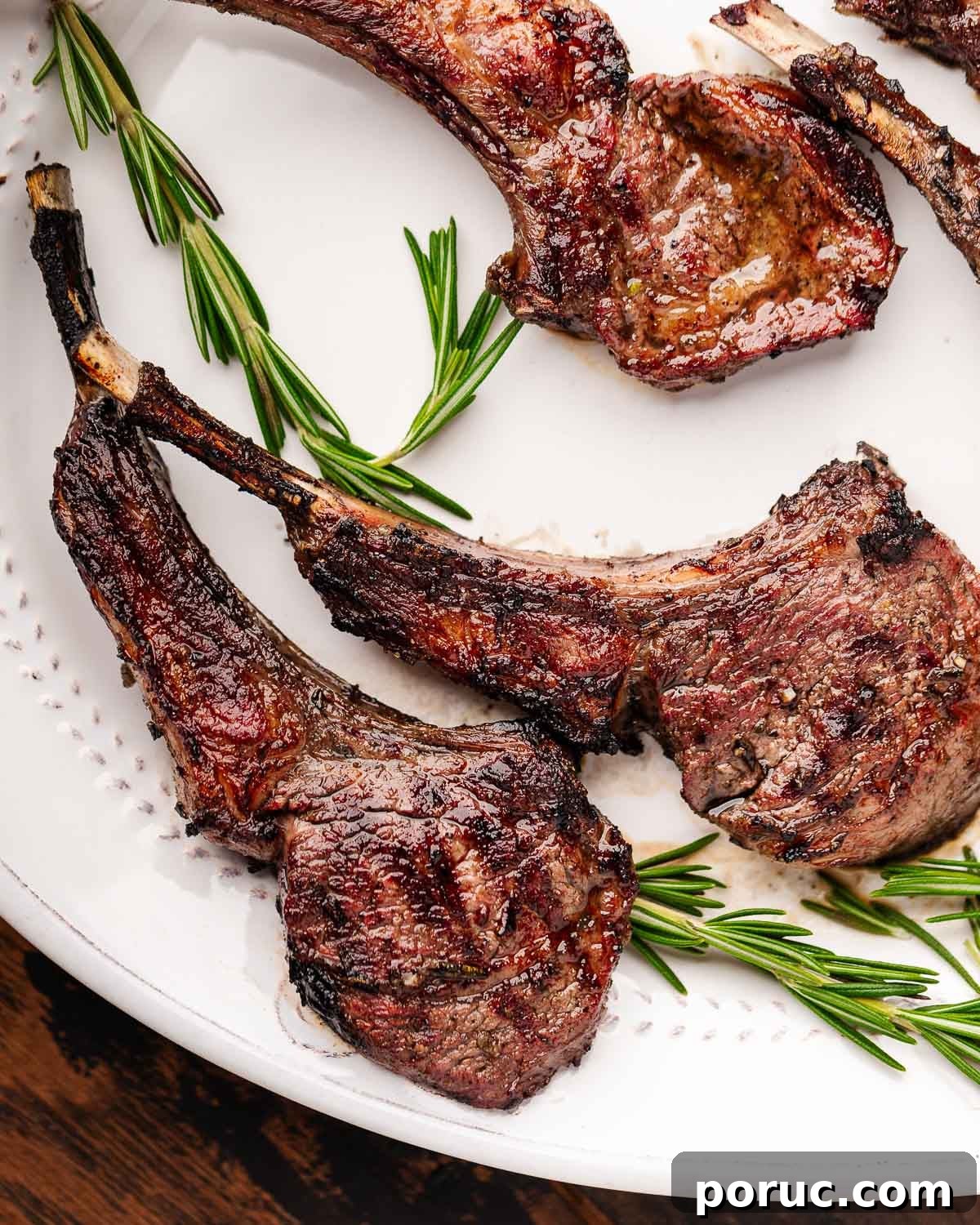 Lemon Garlic Grilled Lamb Rib Chops Recipe for Juicy Flavor 7 Grilled lamb chops on white plate with rosemary garnish.