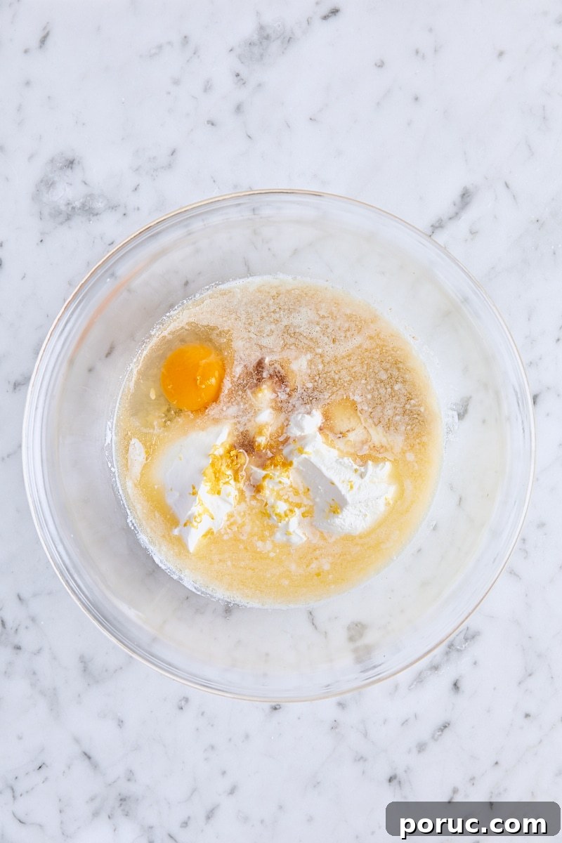 Milk, sour cream, melted butter, egg, lemon zest, and vanilla in glass bowl