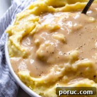 Velvety Gluten-Free Gravy Without Pan Drippings — Thickener Tips 11 a bowl of mashed potatoes with gravy poured over it.