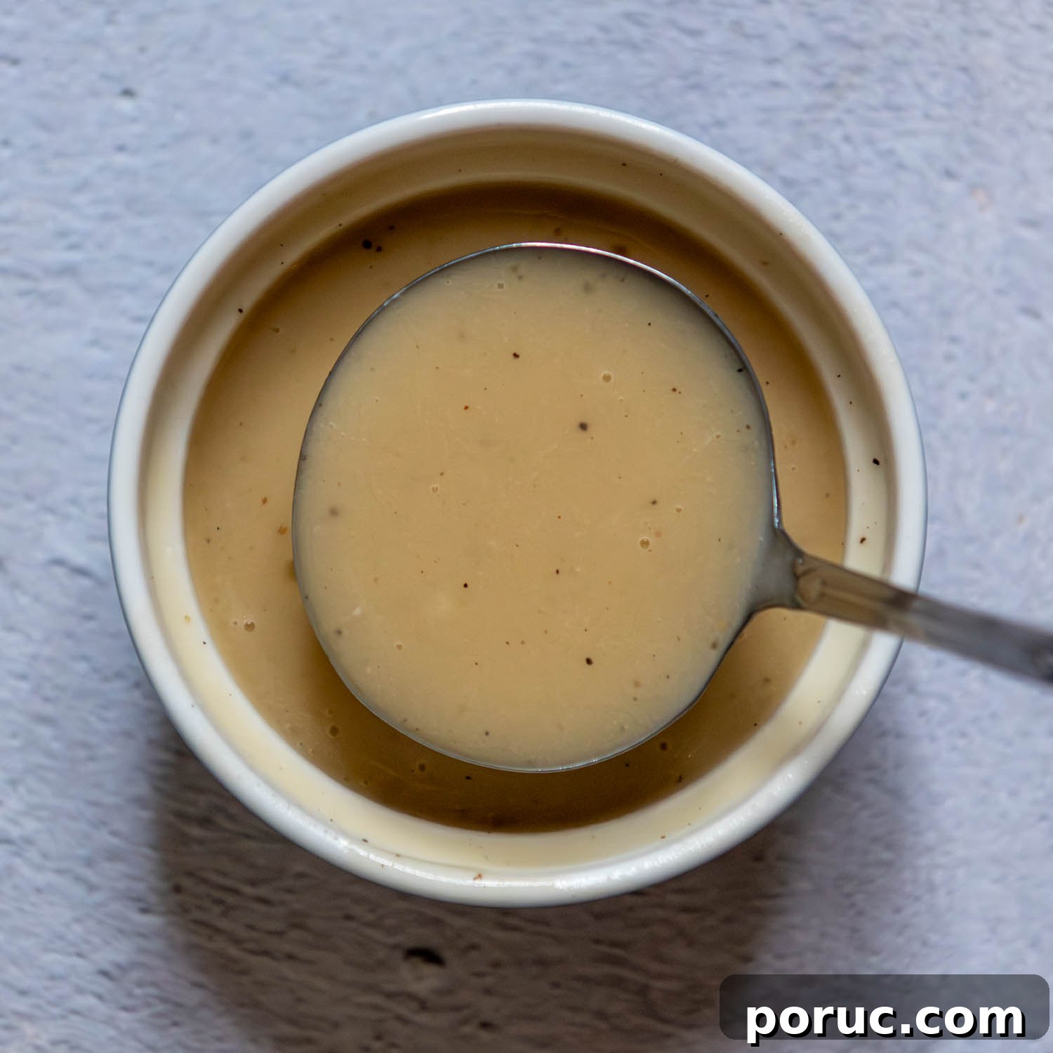 Velvety Gluten-Free Gravy Without Pan Drippings — Thickener Tips 7 small ladle showing consistency of gravy thickened with sweet rice flour.
