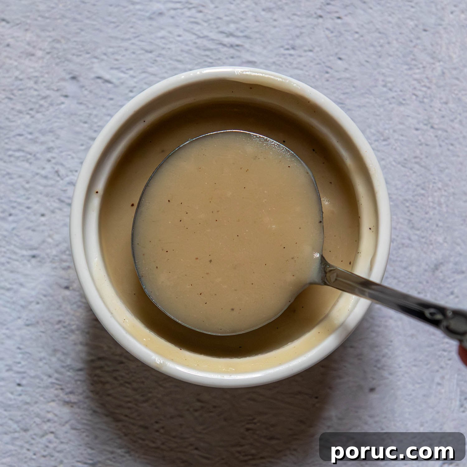 Velvety Gluten-Free Gravy Without Pan Drippings — Thickener Tips 8 small ladle showing consistency of gravy thickened with gluten free flour.