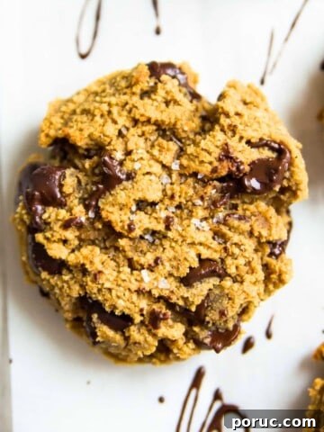 A paleo pumpkin chocolate chip cookie on a baking sheet with sea salt on top of it.