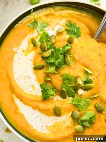 A bowl of pumpkin and sweet potato soup topped with chopped cilantro and pumpkin seeds.