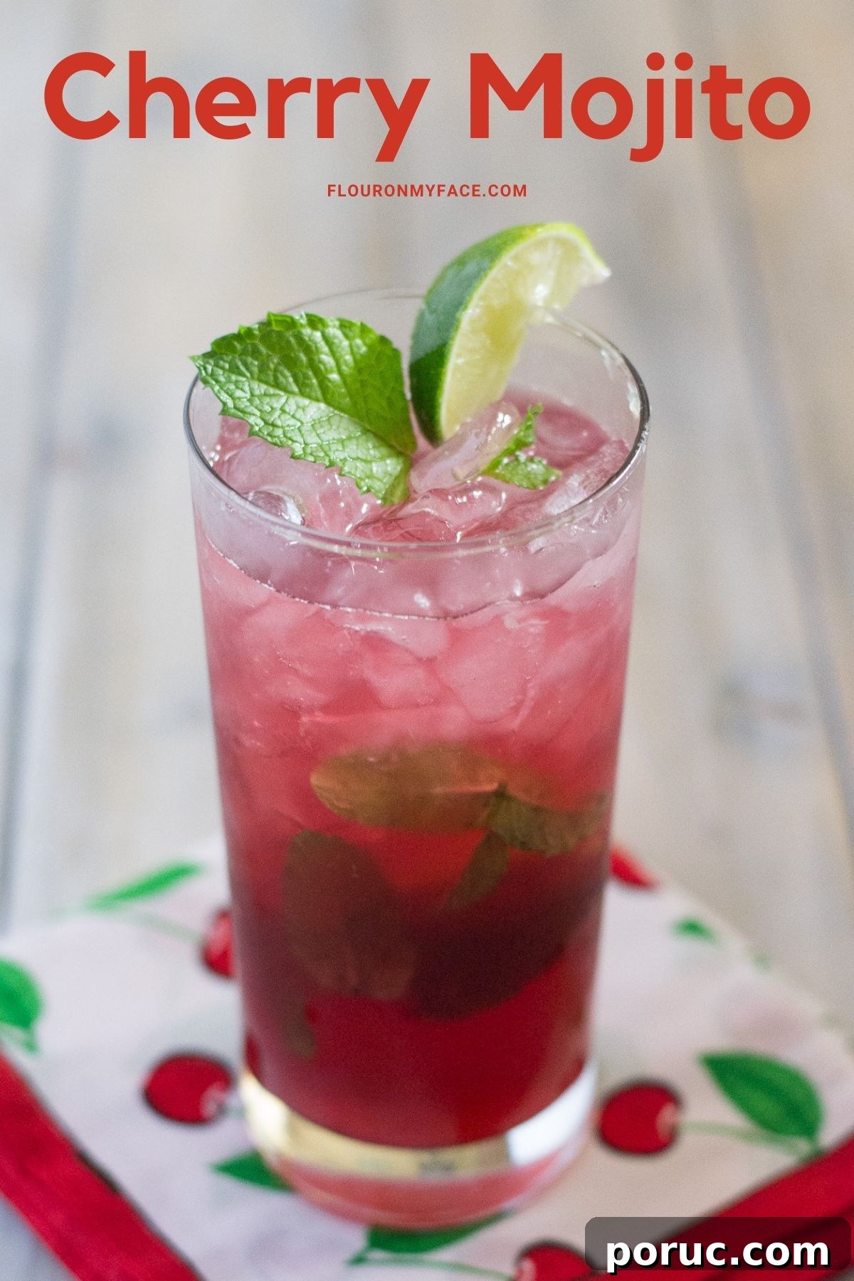 A tall glass on a cloth napkin filled with a sweet cherry mojito.