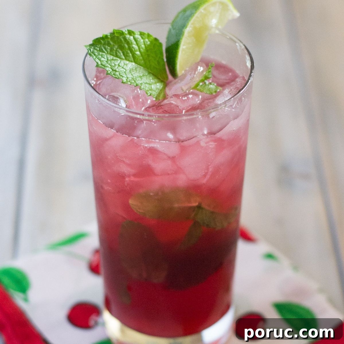 Cherry Mojito in a tall glass garnished with lime and mint.