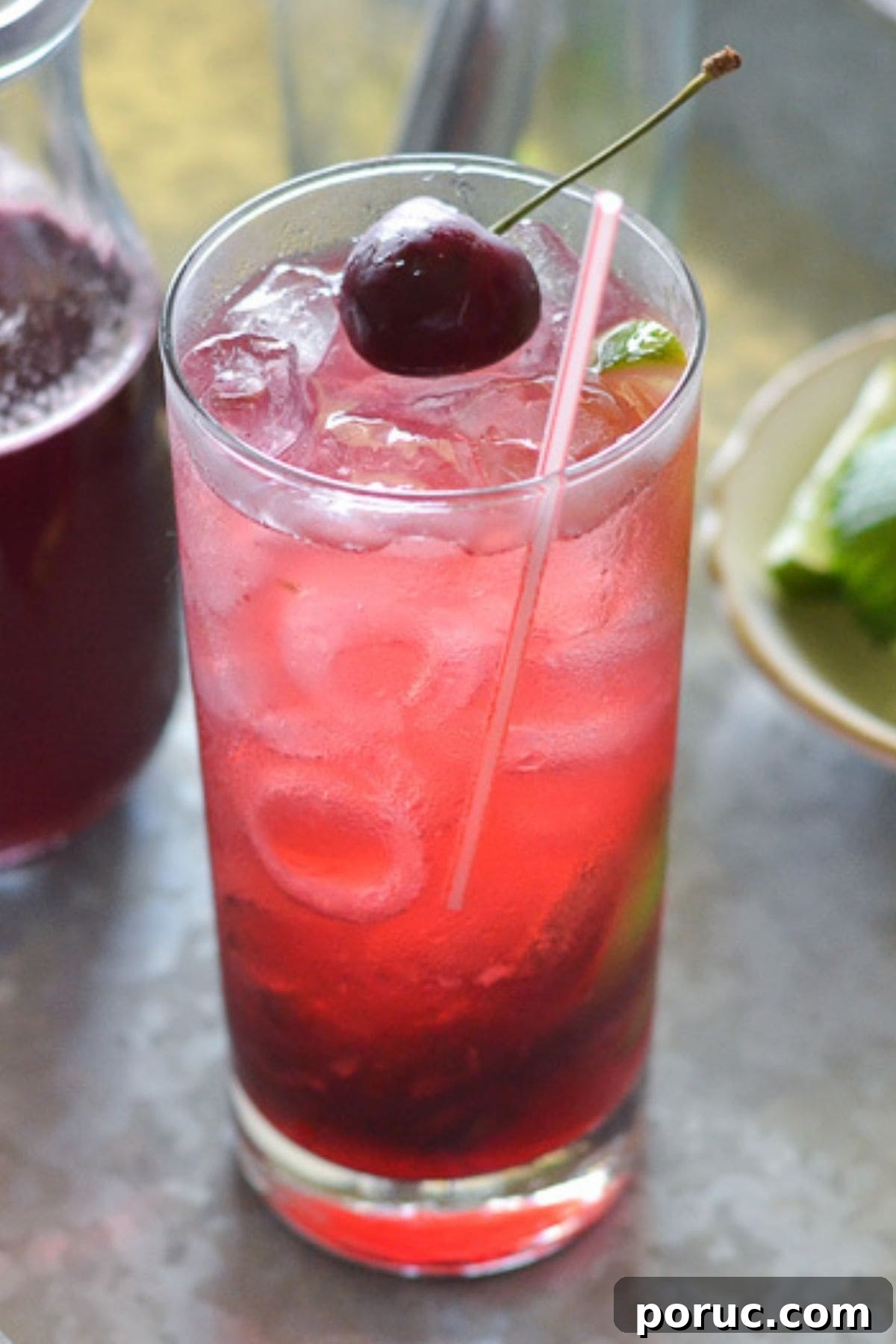 A tall glass on a galvanized metal tray filled with pomegranate cherry mojito.