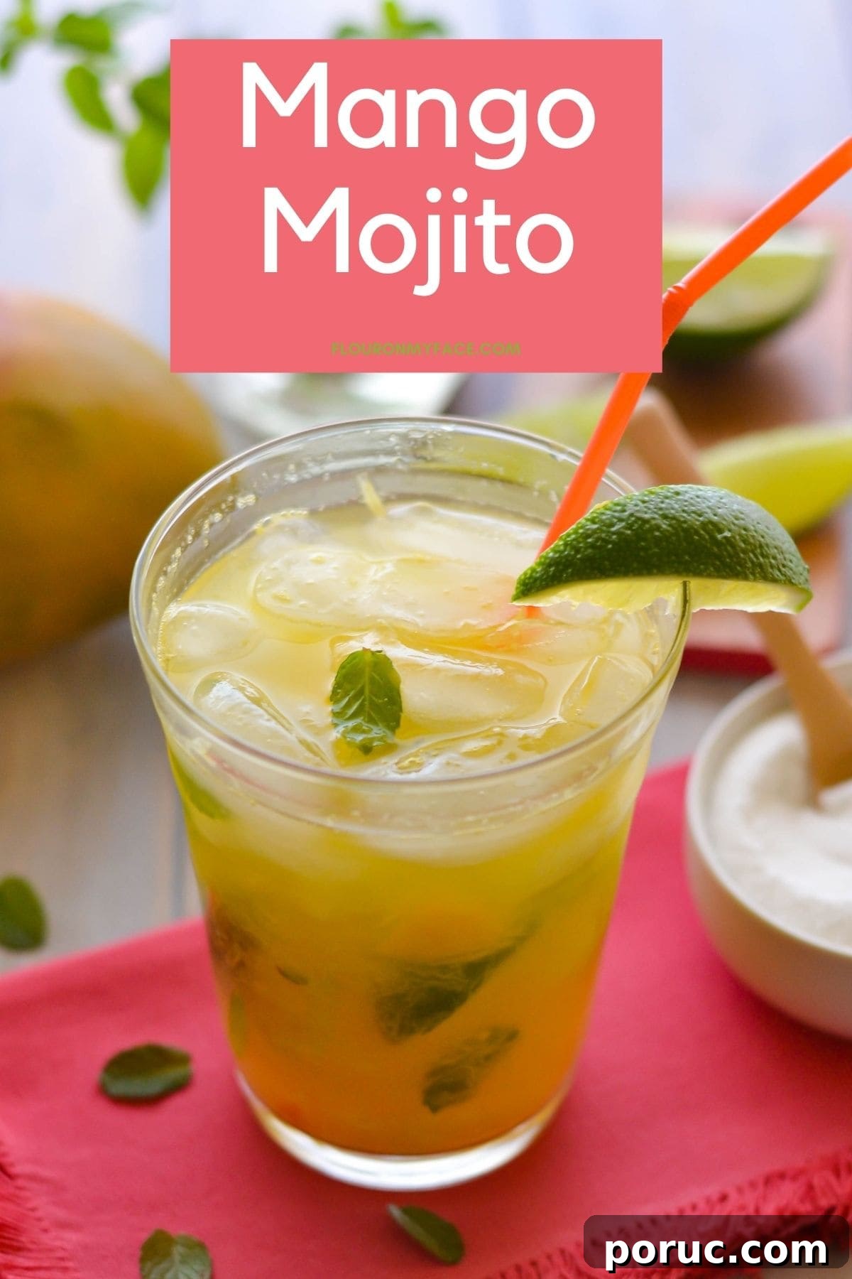 A tall glass filled with Mango Mojito garnished with lime on a cloth napkin.