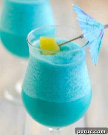 Blue Hawaiian Cocktail in a hurricane glass garnished with pineapple and umbrella.
