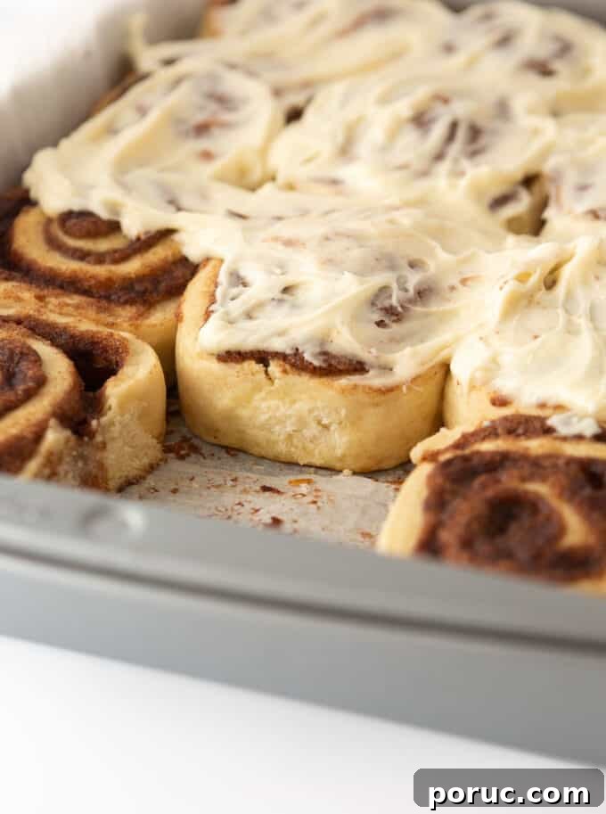 Cream Cheese Frosting Recipe for Perfect Cinnamon Rolls 2 Close-up of cinnamon rolls in a baking pan topped with generous swirls of cream cheese frosting