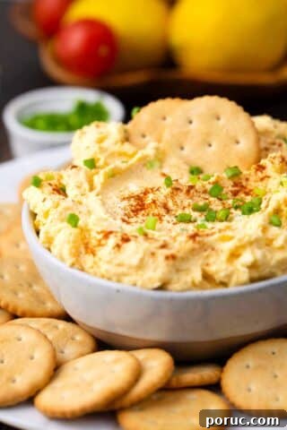 a bowl of deviled eggs dip topped with paprika and chives