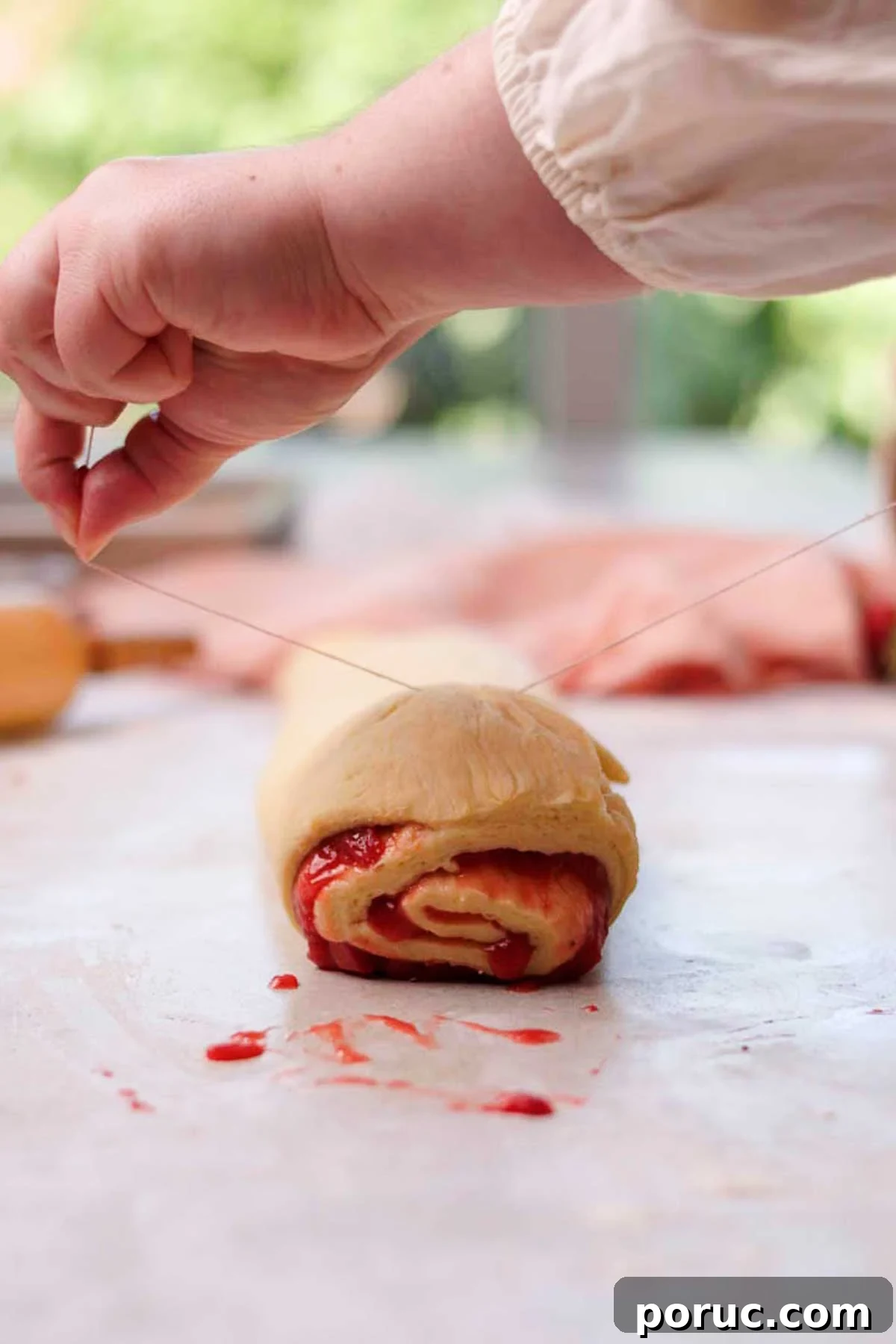Strawberry Cinnamon Roll Recipe — Soft, Sweet, Homemade Treat 15 cutting strawberry cinnamon rolls with a string