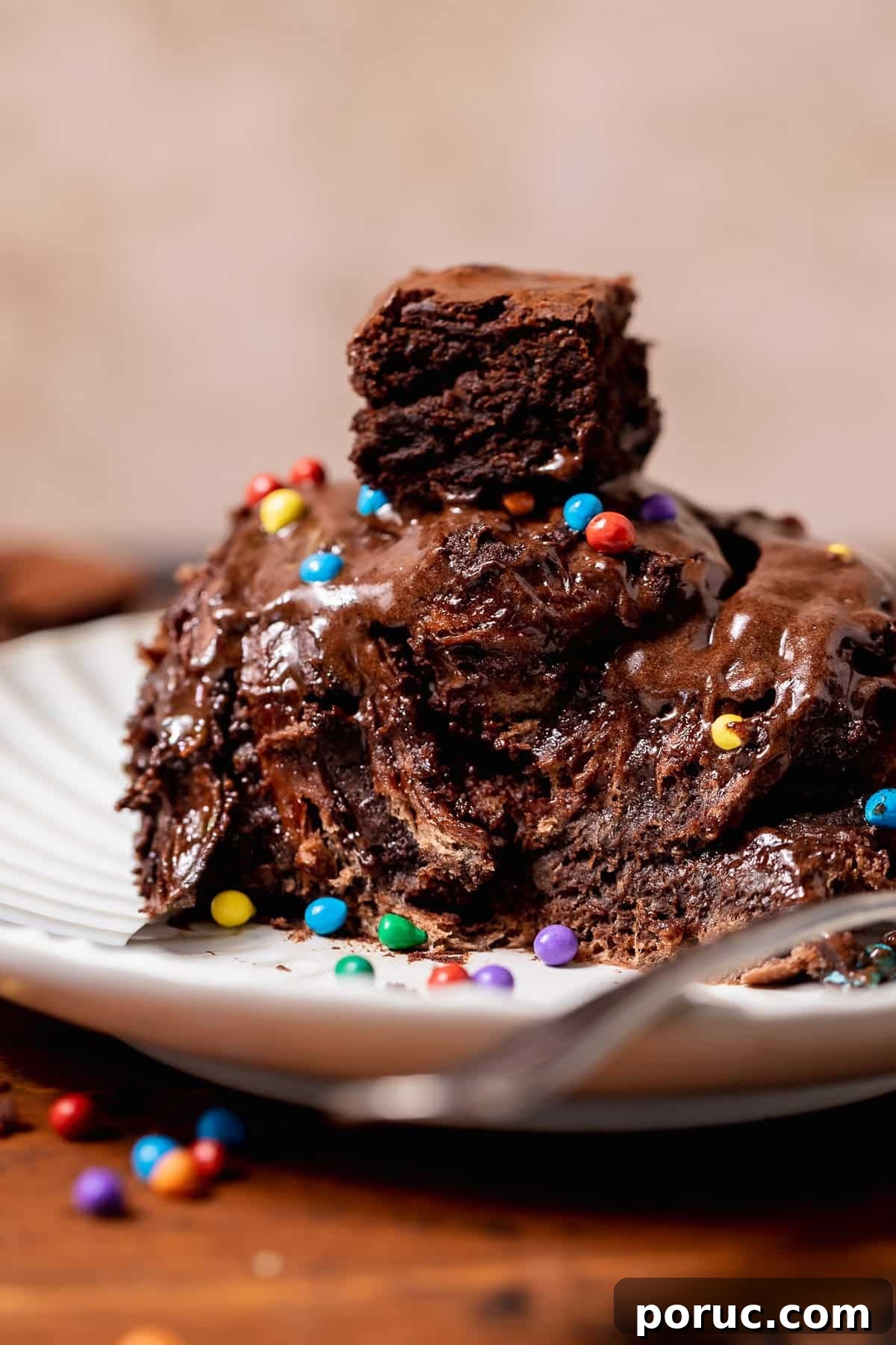 Chewy Cosmic Brownie Roll Recipe with Sprinkle Filling 11 Cosmic brownie roll pulled apart on a plate, revealing gooey chocolate layers, brownie filling, and chocolate frosting inside.