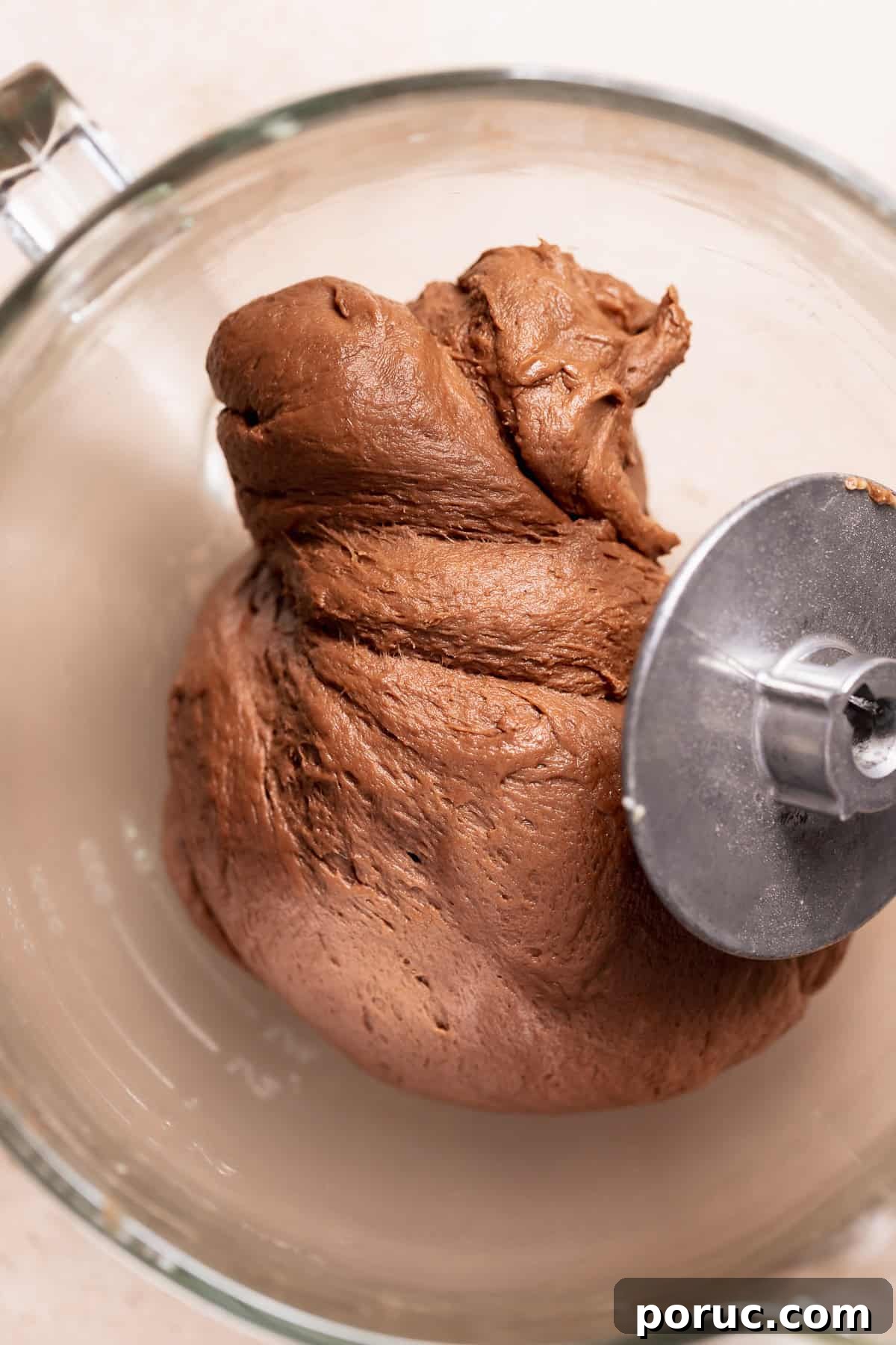 Chewy Cosmic Brownie Roll Recipe with Sprinkle Filling 4 Kneaded chocolate cinnamon roll dough in a glass mixer bowl after mixing, smooth and elastic with a rich chocolate color.
