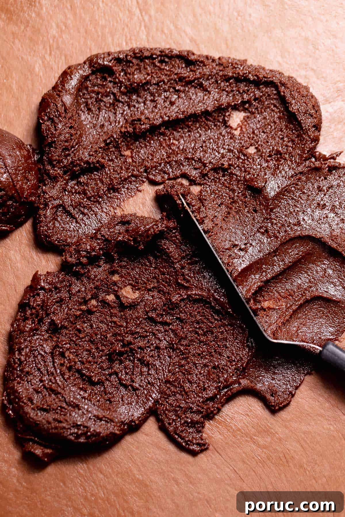 Chewy Cosmic Brownie Roll Recipe with Sprinkle Filling 6 Chocolate brownie filling spread across rolled chocolate dough with a spatula.